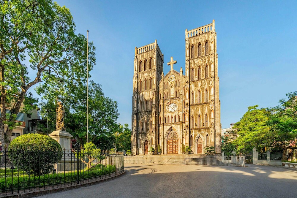 Hanoi St. Joseph Cathedral bathed in golden sunlight and framed by lush greenery